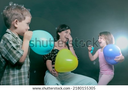 Children's holiday, mother and children laugh merrily and inflate balloons.