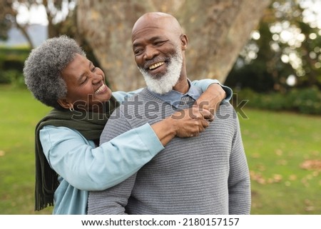 Image of happy african american senior couple posing at camera outdoors in autumn. Family, spending quality time together concept. Royalty-Free Stock Photo #2180157157
