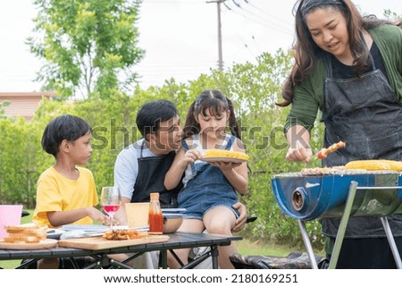 Asian family having barbecue in the backyard. Mother making bbq for her son and daughter. Father talking and playing with kids. Having fun on weekend together