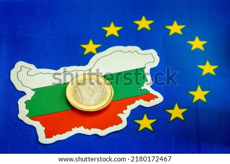 Flag of Bulgaria together with a 1 euro coin on the background of the symbol of the European Union, a creative concept for the accession of Bulgarians to the eurozone Royalty-Free Stock Photo #2180172467