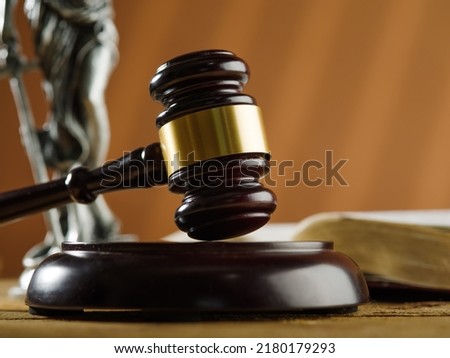 Traditional symbols of a fair American court - a judge's gavel, a statue of Themis and an open book on a beige background. Close-up. Rule of law, law, freedom, justice.