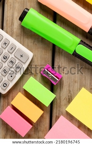 Vertical composition of colorful post it cards and calculator on wooden surface. School equipment, tools, learning and creativity concept.