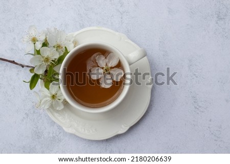 Cup of tea with white flowers on marble table. Minimalist still life in white color. Relaxation, healthy lifestyle, self care concept. Flat lay, top view Royalty-Free Stock Photo #2180206639