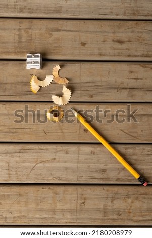 Vertical image of pencil, sharpener and peelings on wooden background. School equipment, tools, learning and education concept.