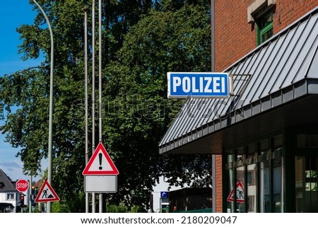 Signboard on the building of the police. Road signs in the background on street.