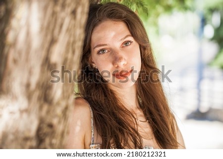 Close up portrait of a young beautiful brunette woman in summer park