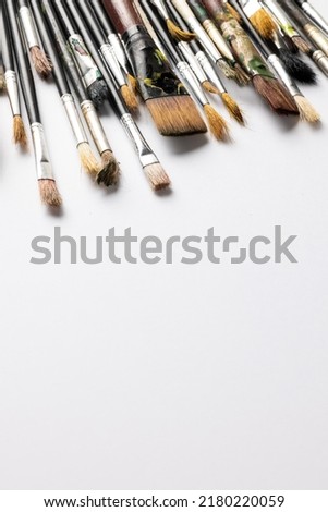 Vertical image of composition of diverse brushes on white surface with copy space. School equipment, tools, learning and creativity concept.