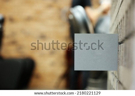 grey postcard or bossiness card with mock up on stylish barbershop or beauty salon background. blurred barber man is cutting and shaving the beard o client