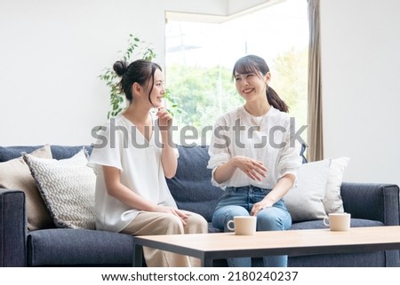 Two young women talking at home Royalty-Free Stock Photo #2180240237