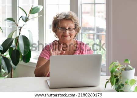 Senior woman sitting at desk talking on video chat using laptop  Royalty-Free Stock Photo #2180260179
