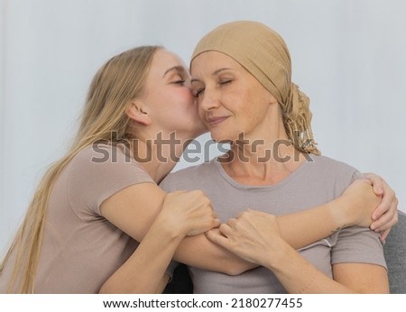 A young and beautiful daughter kiss her mother cancer patient and fortifies her to fight during the chemotherapy. Concept for love and support from beloved and family to breast cancer people