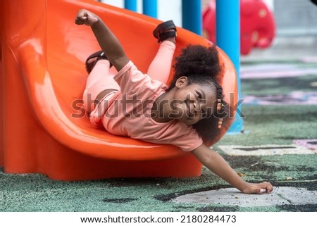 Happy African child girl sliding and playing at outdoor playground in the park on summer vacation, outdoor activity at school or or playground Royalty-Free Stock Photo #2180284473