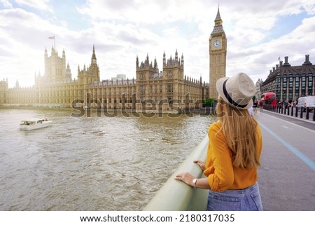Tourism in London. Back view of traveler girl enjoying sight of Westminster palace and bridge on Thames with famous Big Ben tower in London, UK. Royalty-Free Stock Photo #2180317035