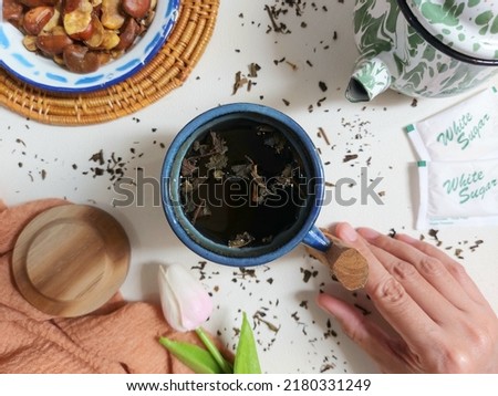 woman hand hold a cup of tea. compeleted with dried leaf tea. healthy drink. aesthetic and minimalist photography concept. isolated background in white