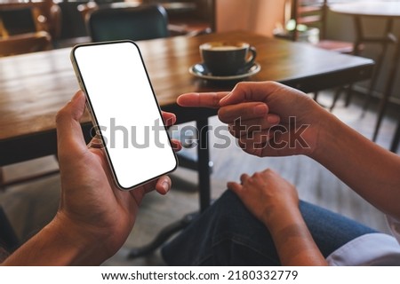 Mockup image of a couple people holding, pointing and looking at the same mobile phone with blank desktop screen