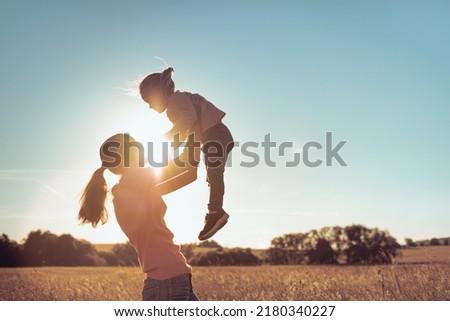 Mother holding her child up to the sunset sky  Royalty-Free Stock Photo #2180340227