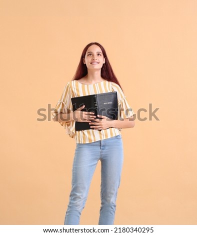 Teenage girl with Holy Bible on beige background