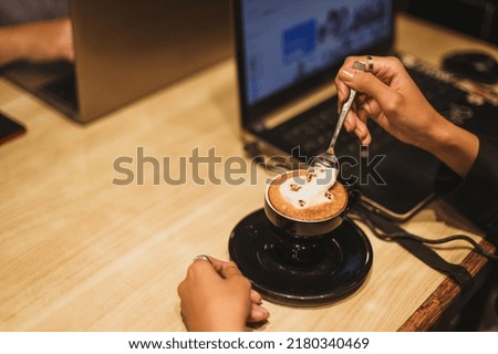 Woman's hand with latte art coffee in shape of cute cat with copy space. 