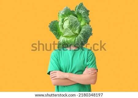 Young man with fresh savoy cabbage instead of his head on yellow background Royalty-Free Stock Photo #2180348197