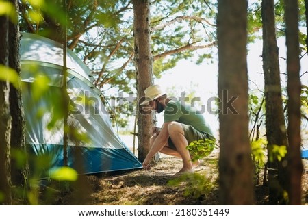 caucasian man wearing a hat putting up a tent. Family camping concept Family camping concept. High quality photo