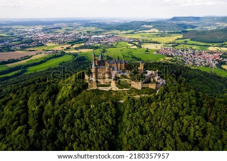 Drone shot of Hohenzollern Castle on forested mountain top in the Swabian Alps in summer. Scenic aerial view of old German Burg. Famous fairytale Gothic landmark in Stuttgart vicinity Royalty-Free Stock Photo #2180357957