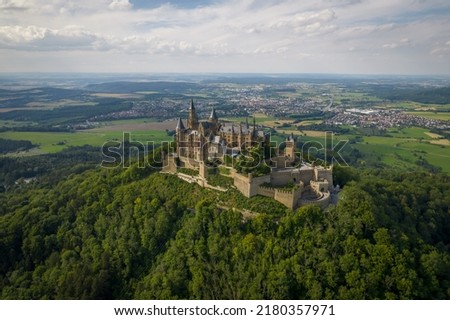 Drone shot of Hohenzollern Castle on forested mountain top in the Swabian Alps in summer. Scenic aerial view of old German Burg. Famous fairytale Gothic landmark in Stuttgart vicinity Royalty-Free Stock Photo #2180357971