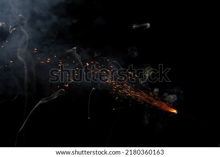 Cracker fuse wire burning with sparkles and flame with stunning smoke patterns with red embers flying in the air, beautifully isolate on black background  Royalty-Free Stock Photo #2180360163