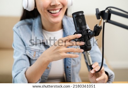 Content creator woman host streaming her a podcast on laptop with headphones and microphone interview cheering guest conversation at broadcast studio. Blogger motivation recording voice over radio.