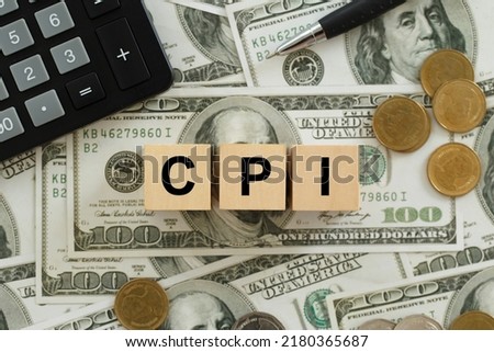 CPI, consumer price index symbol. Wooden blocks with words CPI, consumer price index on dollar bills with a calculator, coins.  Business and CPI, Business and consumer price index concept. Royalty-Free Stock Photo #2180365687