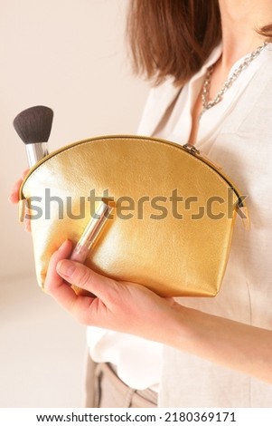 golden leather cosmetic bag with brush close up photo in woman's hand