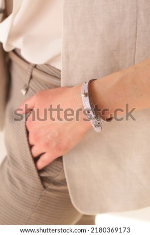 leather studded violet bracelet with hanger on woman hand close up photo on white wall background