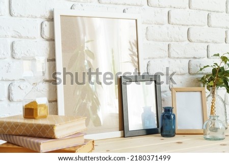 Wooden frame mockup on table with modern vase and books close up