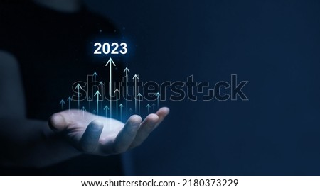 New Goals, Plans and Visions for Next Year 2023. Businessman draws increase arrow graph corporate future growth year 2022 to 2023. Planning,opportunity, challenge and business strategy.  Royalty-Free Stock Photo #2180373229