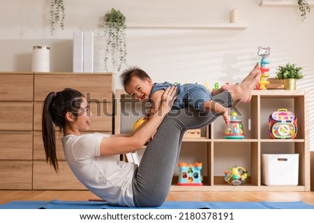 Asian mom playing to adorable infant baby on yoga mat smiling and happiness at home. Mom talking with baby fun and laughing throwing up son in the air exercise together. Relax time.Baby and Mother day Royalty-Free Stock Photo #2180378191