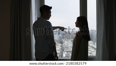 silhoutte of asian couple has a serious argue in front of the window at home