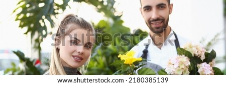 Cute florist workers hold flowers in pots, professional consultants ready to help with choice Royalty-Free Stock Photo #2180385139