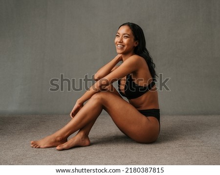 Lovely smiling African American female sitting and showing her well toned body Royalty-Free Stock Photo #2180387815