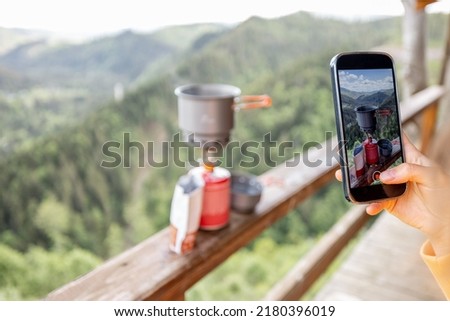 Traveler takes a picture of preparing food for hiking process, boiling water with a gas burner on mountains background