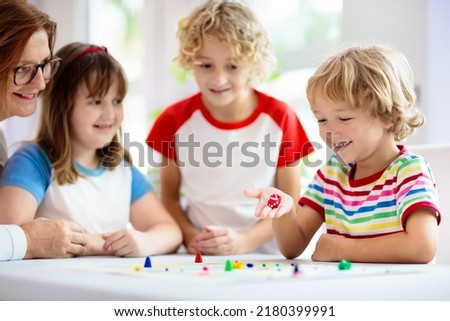 Family playing board game at home. Kids play strategic game. Little boy throwing dice. Fun indoor activity for summer vacation. Siblings bond. Educational toys. Friends enjoy game night. Royalty-Free Stock Photo #2180399991