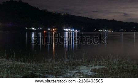 camping tent with light reflection on a calm lake in Waduk Sermo, Kulon Progo, Yogyakarta