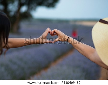 TWO GIRLS MAKING A HEART WITH THEIR HANDS
