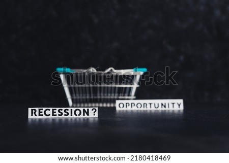 recession or opportunity texts wth shopping basket on dark background with only one in focus, shot at shallow depth of field	