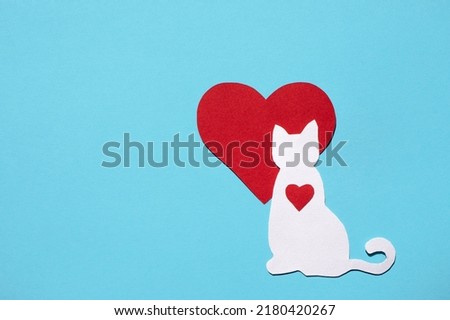 Paper silhouette of a cat and a red heart on a blue background. Flat lay, place for text. Veterinary care or animal care.