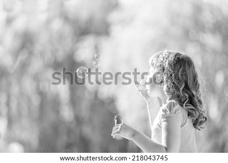 Cute little girl with blowing soap bubbles  in park