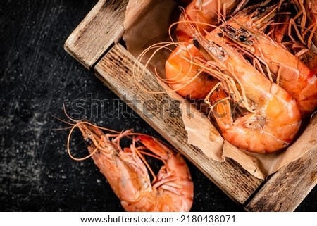 Boiled shrimp on a wooden tray. On a black background. High quality photo