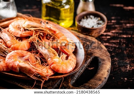 Boiled shrimp in a plate on a cutting board with spices. On a rustic dark background. High quality photo