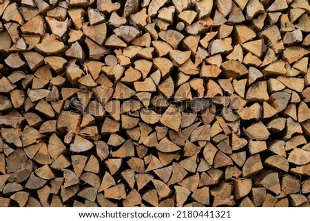 Dry firewood stacked in a neat woodpile. A supply of wood for kindling the fireplace. Wooden texture. The concept of home heating.
