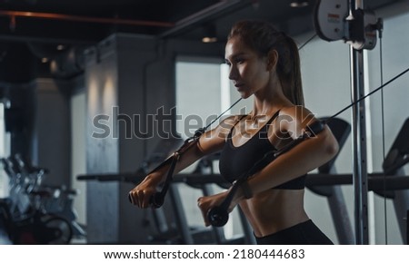 Sporty woman exercising on multistation at gym for arm and shoulders muscles. Fitness exercising in gym. Royalty-Free Stock Photo #2180444683