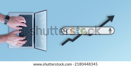 SEO concept, top down view of search bar and person using laptop computer against blue background