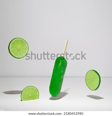 Ice cream on a stick flying upside down. Lime all over in vibrant green colors.Flying above ground making shadow scene. Summer, frozen, refreshing aesthetic idea. Abstract design